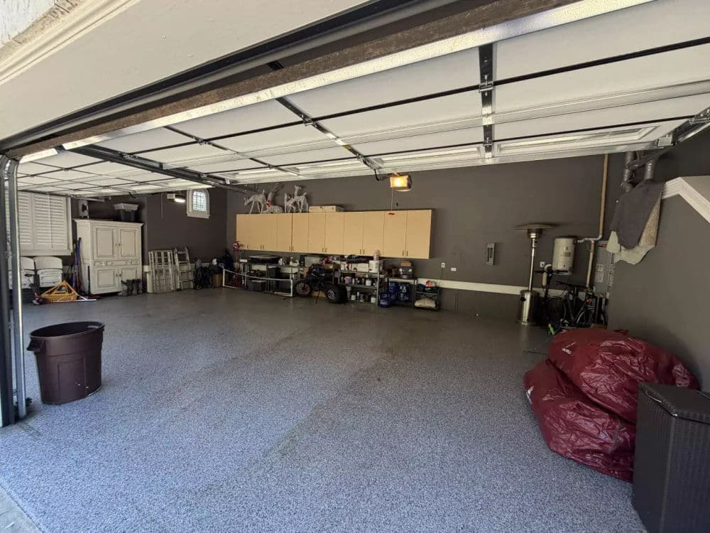 Spacious organized garage with cabinets, clean floor, and storage items.